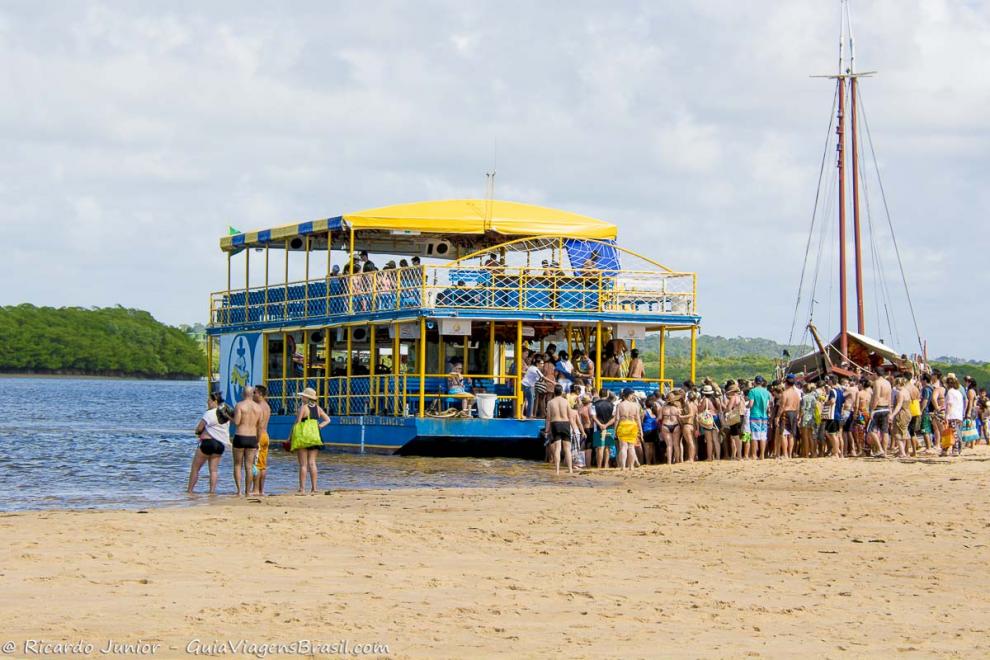 Imagem de turistas entrando no catamarã na Praia de Santo André.